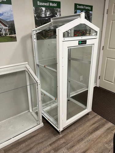 Janco greenhouse indoor/outdoor garden cabinet with glass panels and shelving for plant storage and display.