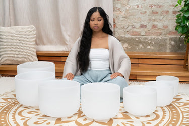 Set of 7 white-frosted crystal singing bowls in various sizes, used for sound healing and chakra balancing with 432 Hz tuning.