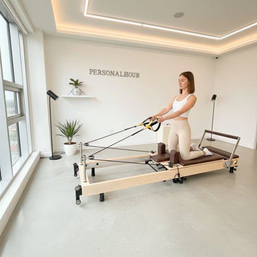 Personal Hour Janet Elite Plus foldable Pilates reformer machine with adjustable resistance and padded carriage for full-body workouts.