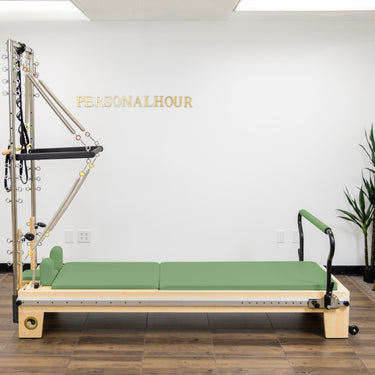 Personal Hour Nano Elite Half Trapeze Pilates Reformer with adjustable tower and green upholstery for studio Pilates workouts.