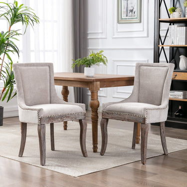 Set of two beige A&A Furniture Ultra Side Dining Chairs with thick fabric and bronze nail head trim, designed by HouseOfZazla
